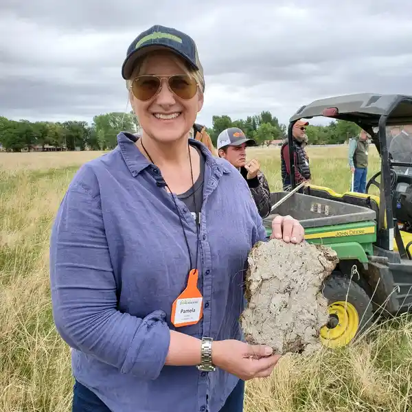 A woman holding a piece of rock in the middle of an open field.