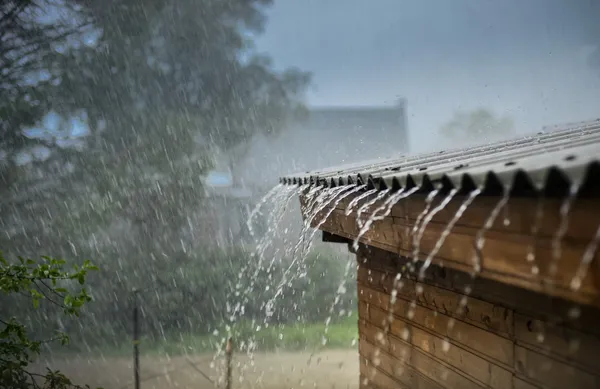 A rain shower is pouring on the roof of a house.